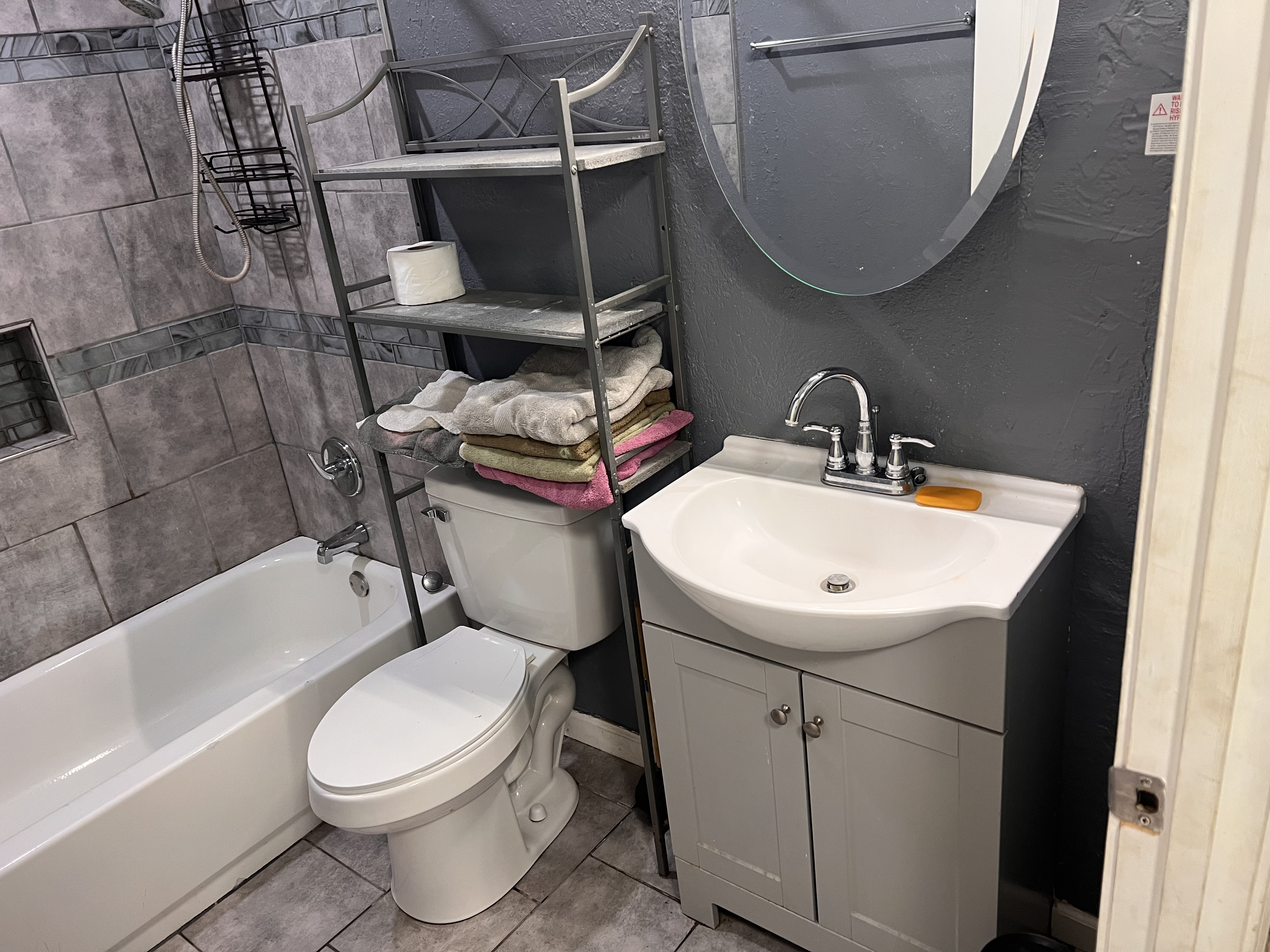 Bathroom with a bathtub and shower, toilet, sink, mirror and towel shelving