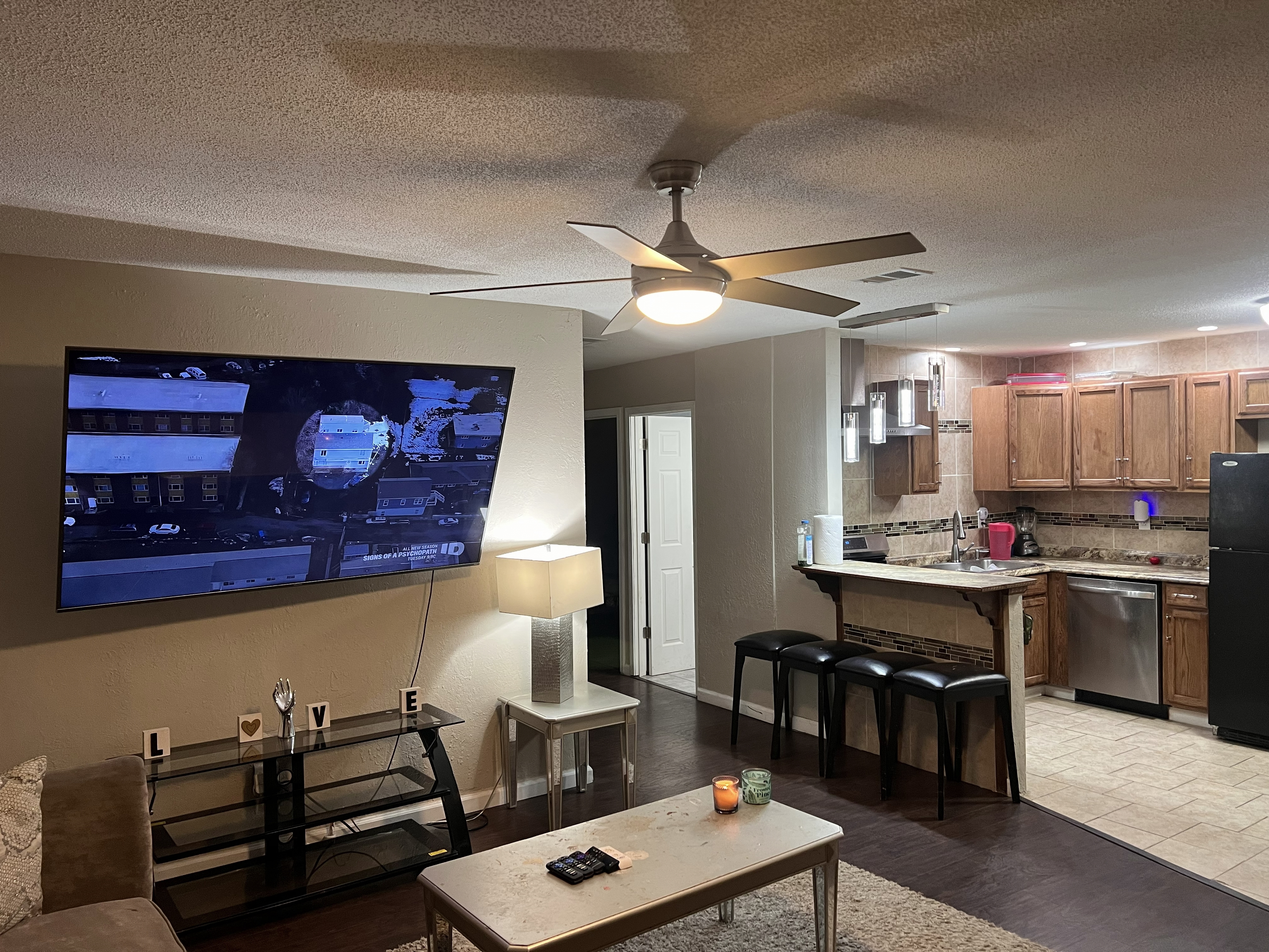 Living room with a flat-screen TV beside the kitchen and breakfast bar